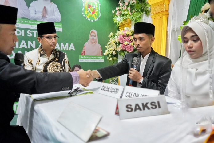 Wali Kota Medan Rico Tri Putra Bayu Waas saat menjadi saksi pernikahan pasangan Jaya Pratama dengan Tasya Rivani Putri yang digelar di Stand Kementerian Agama Kota Medan yang berada di lokasi Musabaqoh Tilawatil Qur'an (MTQ) ke-58 Kota Medan, Kamis (24/04/2025) malam. (Foto : Ist)