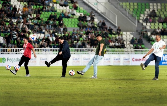 Teks Foto :  Gubernur Sumatera Utara (Sumut) Bobby Nasution bersama Ketua Umum PSSI Erick Thohir menendang bola pertanda dimulainya Pegadaian Championship musim 2025/2026 di Stadion Utama Sumatra Utara, Jumat (12/09/2025). Pada pertandingan perdana ini PSMS Medan harus takluk oleh Persekat Tegal dengan skor tipis 0-1 yang tercipta di akhir babak Ke-2. (Foto : Ist) 