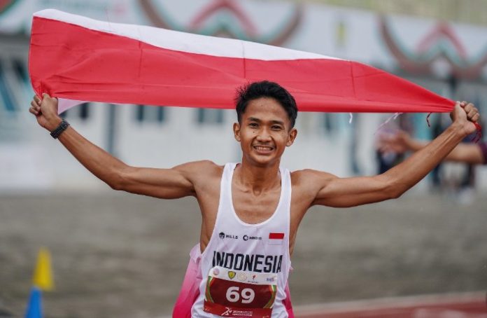 Teks Foto : Pelari Indonesia Yad Hafizudin berlari mengibarkan bendera Merah Putih usai memenangkan lomba lari kategori pria 1.500 meter U 20 pada event kejuaraan Atletik Asia Tenggara U-18 & U-20 di Stadion Madya Atletik Kawasan Sport Centre Sumut, Kabupaten Deliserdang, Provinsi Sumatera Utara, Sabtu (15/11/2025). Pelari asal Lombok Timur menjadi penyumbang medali emas pertama pada event ini dengan catatan waktu 3:56.94.(Foto : Ist)