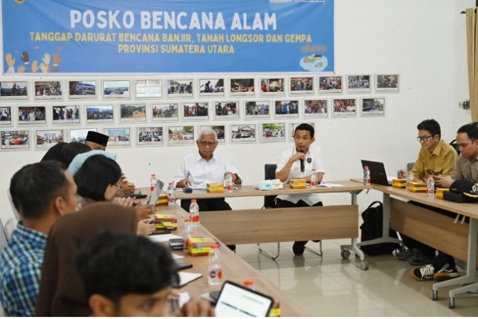 Teks Foto : Wakil Gubernur Sumatera Utara (Wagub Sumut) Surya bersama Kemenko Bidang Infrastruktur dan Pembangunan Kewilayahan (Kemenkoinfra) melaksanakan rapat koordinasi terkait tentang percepatan pemulihan pasca bencana di Sumut terutama pada sarana prasarana dan pemukiman warga yang terdampak banjir dan longsor, di Posko Darurat Bencana Sumut, Jalan AH Nasution Medan, Jumat (19/12/2025). (Foto : Ist)