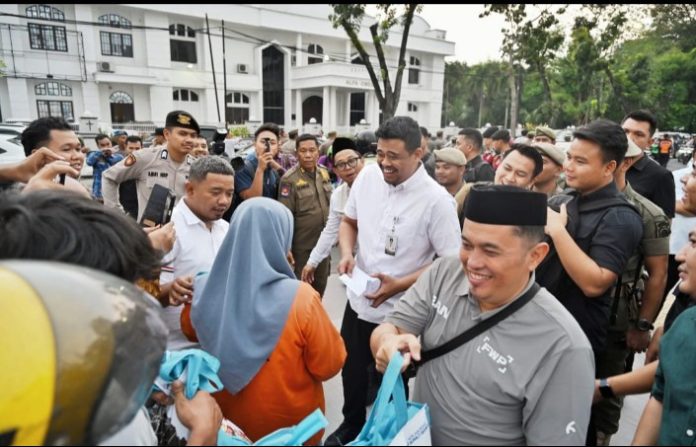 Teks Foto : Gubernur Sumatera Utara (Sumut) Muhammad Bobby Afif Nasution didampingi Zainul Bendahara Wartawan Pemprov Sumatera Utara membagikan tunjangan hari raya (THR) kepada masyarakat di Kota Medan, Selasa (17/3/2026). Bantuan yang diberikan berupa kebutuhan pokok (sembako) dan santunan uang tunai.(Foto : Ist)